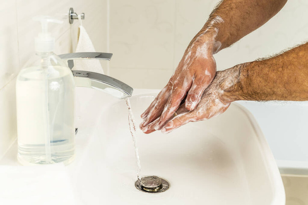 Мужчина моет руки дезинфицирующим гелем для профилактики коронавируса, гигиены, чтобы остановить распространение коронавируса
. - Фото, изображение