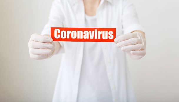 Εστία του κερατοειδούς, κόκκινη προειδοποιητική πινακίδα με το κείμενο Coronavirus σε χέρια γιατρού με λευκό παλτό, γάντια, μάσκα προσώπου. Ιός Καραντίνας Στεφανιαίος Επιδημικός. Γρίπη έξαρσης του ιού του κερατοειδούς. Μεγάλο banner. - Φωτογραφία, εικόνα