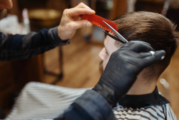 Il barbiere con pettine e forbici fa un taglio di capelli a un cliente. Il barbiere professionista è un'occupazione alla moda. Parrucchiere maschile e cliente in stile retrò parrucchiere
 - Foto, immagini