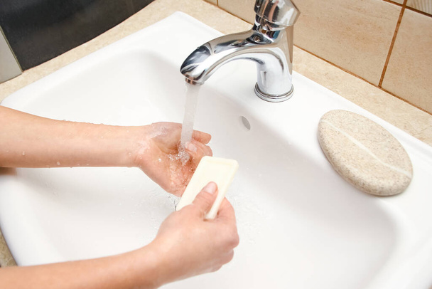 Lavarsi le mani con il sapone sotto il rubinetto con acqua - Foto, immagini