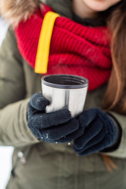 La fille boit une boisson chaude avec des guimauves en hiver dans la forêt. Une promenade d'hiver confortable à travers
 - Photo, image