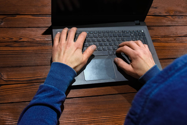 Haker z komputerowcem siedzącym przy stole w kapturze - Zdjęcie, obraz