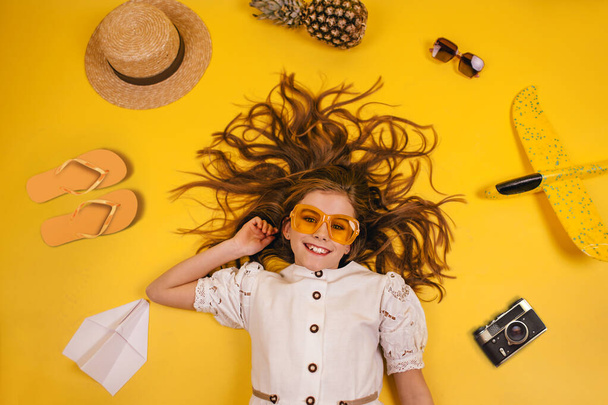Top view of a girl who travels, collection of leisure items on a yellow background, concept of traveling outside the country - Foto, Bild
