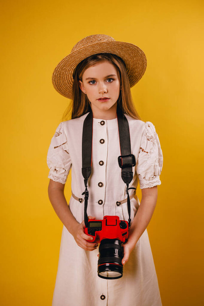 Young girl holding a red camera in her hands and looking at the photographer - Fotografie, Obrázek
