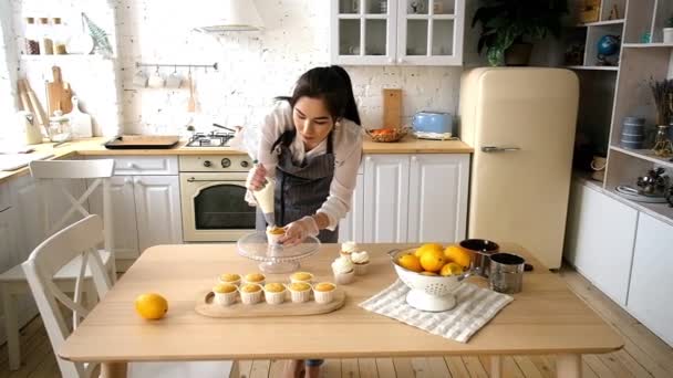 Mujer pastelera decora cupcakes. En la cocina
 - Imágenes, Vídeo