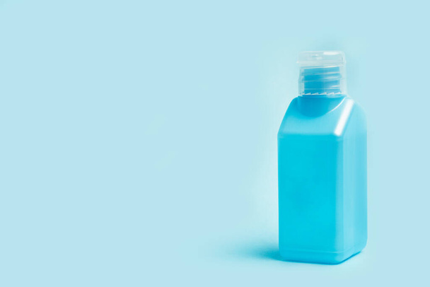 Een fles gel alcohol op een lichtblauwe achtergrond - Foto, afbeelding