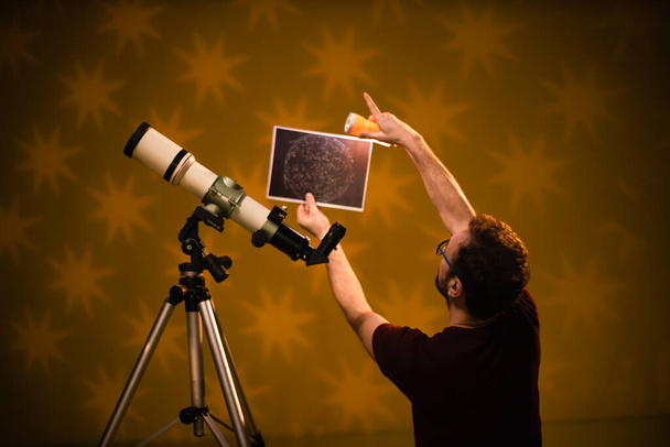 De mens kijkt naar de sterren door middel van een telescoop-astrologie concept, horoscoop voorspellingen over de toekomst. - Foto, afbeelding