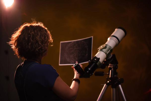 Kobieta spoglądająca w gwiazdy przez teleskop. Koncepcja astrologii, przewidywania horoskopu o przyszłości.. - Zdjęcie, obraz