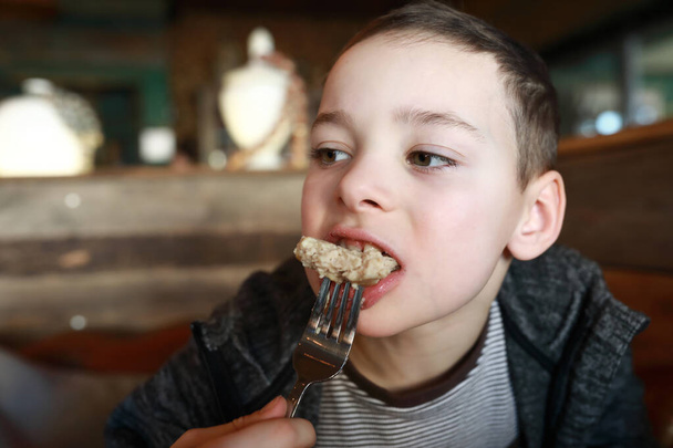 Boy eats chicken cutlet in a restaurant - Zdjęcie, obraz