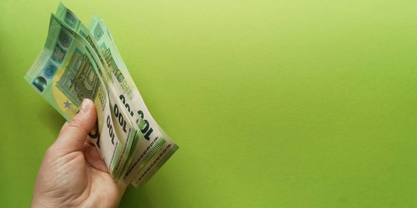 Lewy stos 100 banknotów euro wyemitowanych w 2019 r. na zielonym tle. Skupianie się, przestrzeń kopiowa.Koncepcja zysku Dochód w walucie europejskiej.Motywacja do zarabiania pieniędzy - Zdjęcie, obraz