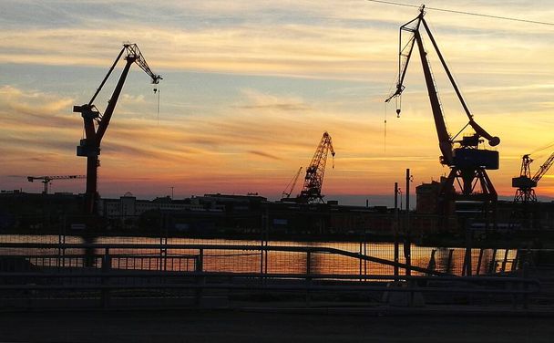 Silhouettes of Cranes at Cargo Harbour Sunset in Gothenburg, Sweden - Fotó, kép
