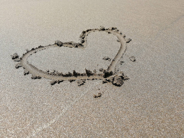 Um sinal de coração pintado na areia da praia. Conceito de amor, férias, romance, Dia dos Namorados
 - Foto, Imagem
