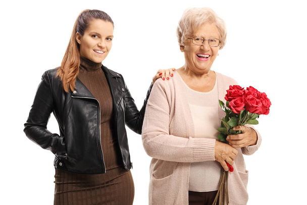 Oudere vrouw met een bos van rode rozen en poseren met een jonge vrouw geïsoleerd op witte achtergrond - Foto, afbeelding