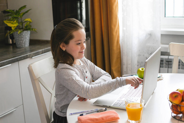 Całkiem słodkie uczennica uczy się w domu za pomocą laptopa. Szkoła domowa koronawirusa, edukacja online, edukacja domowa, koncepcja kwarantanny - Zdjęcie, obraz