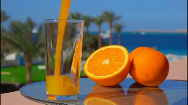 Свежий апельсиновый сок наливают в стакан на фоне моря
 - Кадры, видео