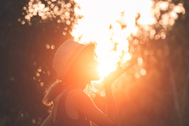Frau pustet Kuss und hält Sonne in erzwungener Perspektive. - Foto, Bild