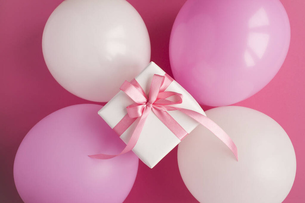 Gift with  pink and white balloons  on the pink background. Top view. Closeup. - Фото, зображення