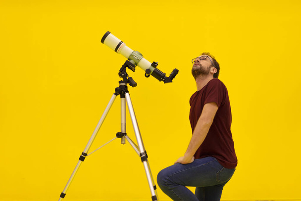 Astrónomo aficionado mirando las estrellas con un telescopio. Concepto de astronomía y astrología. Estudio sobre fondo amarillo
. - Foto, Imagen