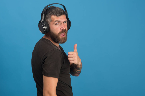 Music and leisure concept. Dj with beard wears headphones - Фото, изображение
