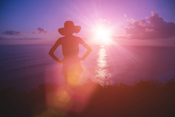 Sylwetka kobiety z tropikalnym zachodem słońca nad oceanem. - Zdjęcie, obraz