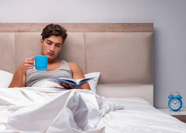 Uomo che legge libro nel letto
 - Foto, immagini