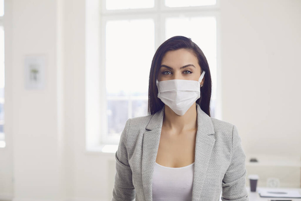Danger of infection of the virus coronavirus infection. Businesswoman in medical mask at office - Foto, afbeelding