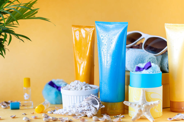 Sonnencremeflaschen, Gläser, Seesterne auf gelbem Hintergrund. Schönheit und Pflege im Sommer. - Foto, Bild
