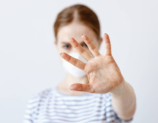 Rozmazané dáma v lékařské masce ukazující stop gesto proti šedému pozadí během koronavirus epidemi - Fotografie, Obrázek