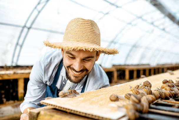 Agricultor trabajando en la granja con caracoles
 - Foto, Imagen