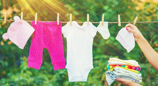 赤ちゃんの服を洗う。リネンは新鮮な空気の中で乾燥します。選択的な焦点。自然. - 写真・画像