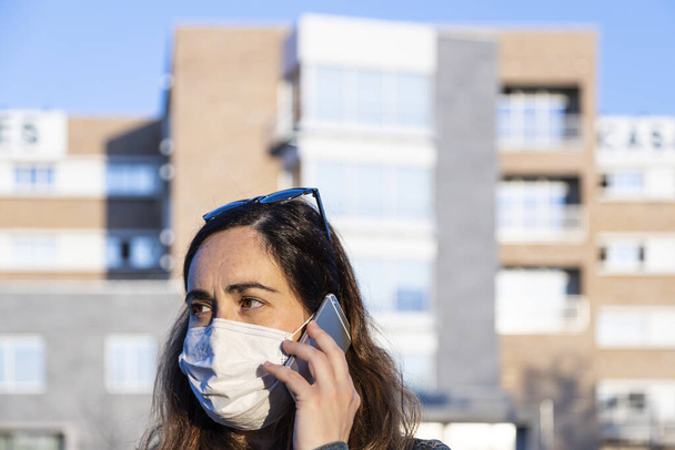 mujer joven hablando en su teléfono inteligente con un respirador en la calle
 - Foto, imagen