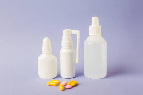 Vaporiser pour le nez, un remède contre le mal de gorge, antiseptique. Flacons blancs avec médicaments sur fond lilas
. - Photo, image