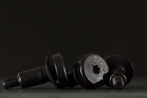 These identical, black-coated car parts are specially designed for use in the automotive industry. These special screw connections are visible on a black background. - Photo, Image