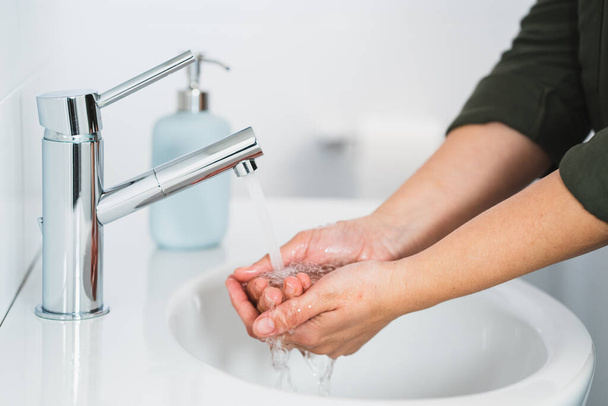 Hygiëne. Schoonmaakhanden. Handen wassen met zeep. Jonge vrouw wassen handen met zeep over wastafel in de badkamer, close-up. Covid 19. Coronavirus. - Foto, afbeelding