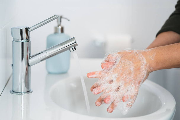 Hijyen. Temizlikçi Eller. Ellerimi sabunla yıkıyorum. Banyoda ellerini sabunla yıkayan genç bir kadın, yakın plan. Covid 19. Coronavirüs. - Fotoğraf, Görsel