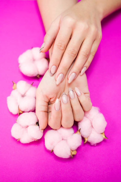 Beautiful women's manicure in delicate tones, on a bright background with gently pink cotton. Place for the inscription. View from above. - Foto, immagini