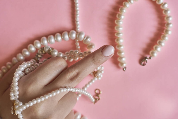 Beautiful female hands with manicure holding pearls. Woman showing hands with stylish trendy female manicure. Hand skin care - Photo, image