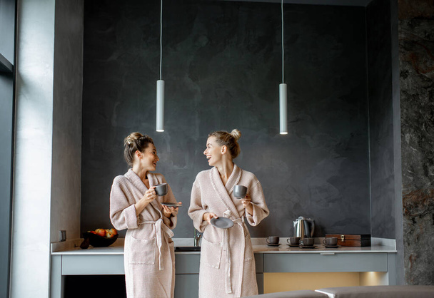 Women in bathrobes relaxing on the kitchen - Foto, Imagem