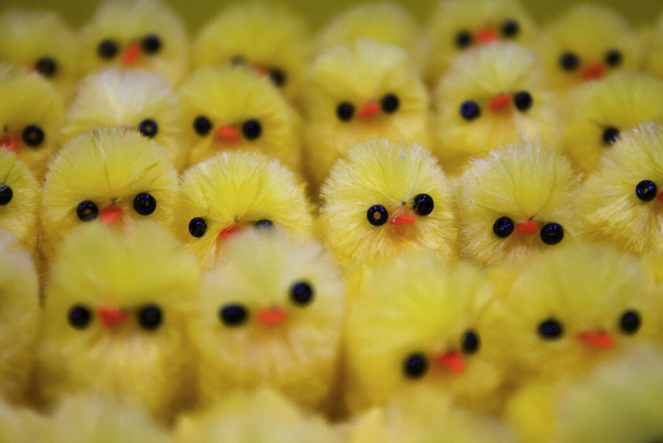Πολλά κίτρινα, πλαστικά κοτόπουλα στη σειρά στο σούπερ μάρκετ με μαύρα μάτια και πορτοκαλί ράμφος - Φωτογραφία, εικόνα