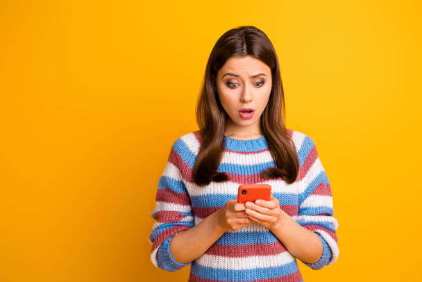 Close-up portrait of her she nice attractive worried disappointed brown-haired girl holding in hands cell reading fake news bad mark isolated on bright vivid shine vibrant yellow color background - Zdjęcie, obraz