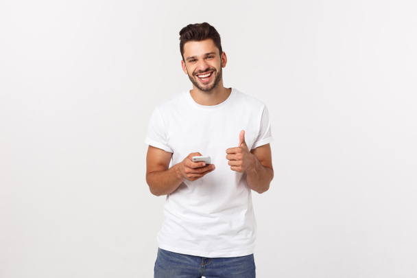 Glücklicher lässiger Mann mit Smartphone und Daumen hoch über grauem Hintergrund - Foto, Bild