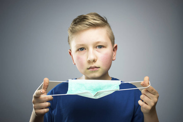 A child in an antiviral mask. The boy puts on an antiviral mask. - Foto, Imagen