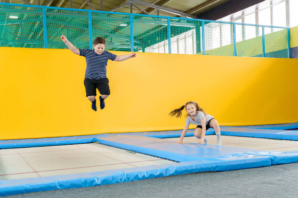 Happy smiling small kids jumping on indoors trampoline in entertainment center - Foto, Imagen