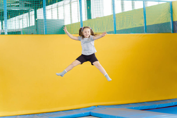 gelukkig klein meisje springen op trampoline in fitness center - Foto, afbeelding