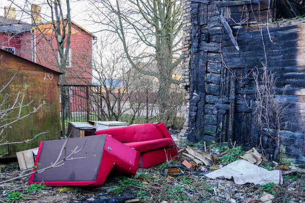 παλιό ξύλινο σπίτι μετά τη φωτιά, κόκκινο καναπέδες κοντά στο σπίτι - Φωτογραφία, εικόνα