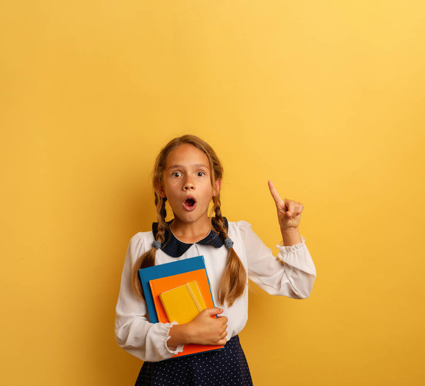 Young student is with shocked expression and indicates something. Yellow background - Photo, Image