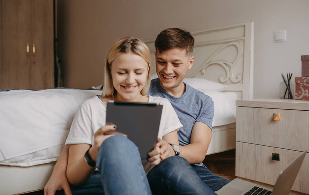Lovely caucasian couple sitting on the floor and smiling while using a tablet - Photo, Image