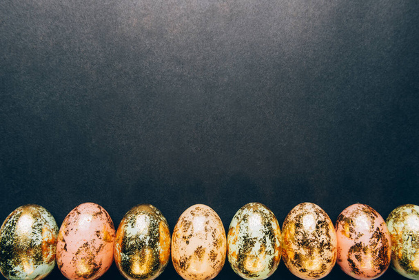 Φυσικά χρυσά Speckled πασχαλινά αυγά παστέλ χρώματα σε μαύρο φόντο. Happy Easter card concept, μινιμαλιστικός σχεδιασμός, αντίγραφο χώρου - Φωτογραφία, εικόνα