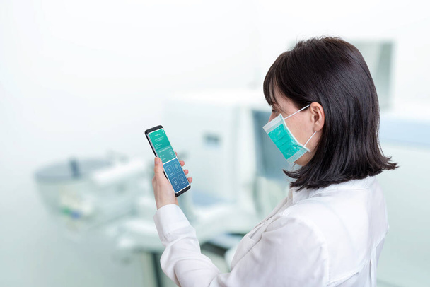 Frau im Krankenhauslabor hält Telefon mit den Befunden einer Patientin, die positiv auf Coronavirus getestet wurde - Foto, Bild