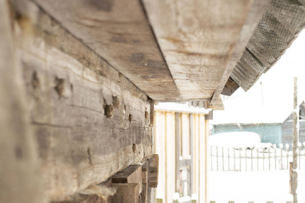 вид сбоку на деревянную стену из бруса и кровельных досок старого деревянного дома
 - Фото, изображение